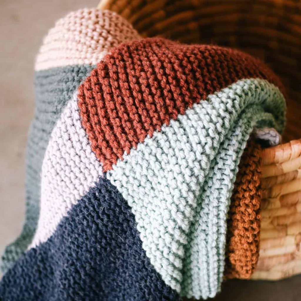 Muted colors of a patchwork knitted blanket.